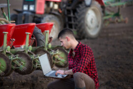 Young,Farmer,With,Laptop,Squatting,In,Field,In,Front,Of