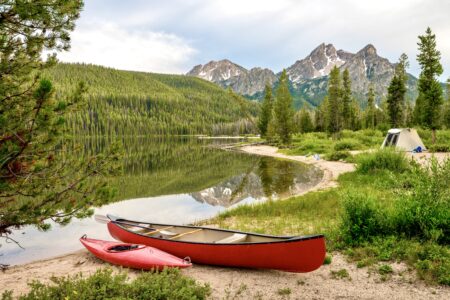 Recreation in the Idaho mountains with a tent and read boats on a lake