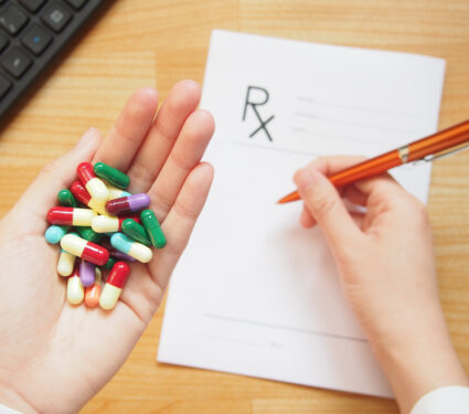 Female,Doctor,Hand,Holding,Different,Colorful,Capsule,And,Writing,Prescription