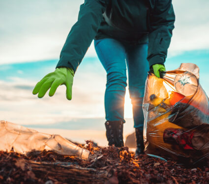 A,Volunteer,Collects,Garbage,On,A,Muddy,Beach.,Close-up.,The