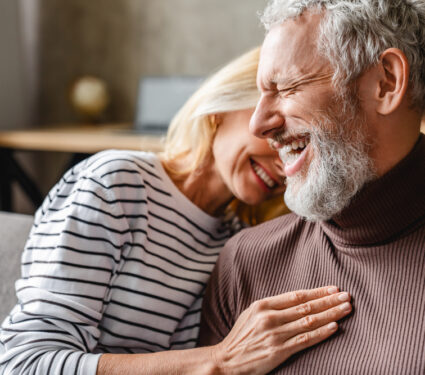 Happy,Laughing,Middle,Aged,Couple,Bonding,While,Relaxing,Sitting,On