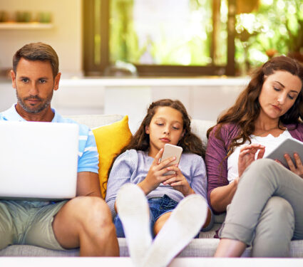 Distracted,By,Devices.,Cropped,Shot,Of,A,Family,Sitting,On