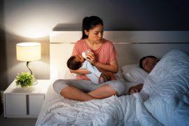 Tired,Mother,Feeding,Milk,Bottle,To,Newborn,Baby,While,Looking