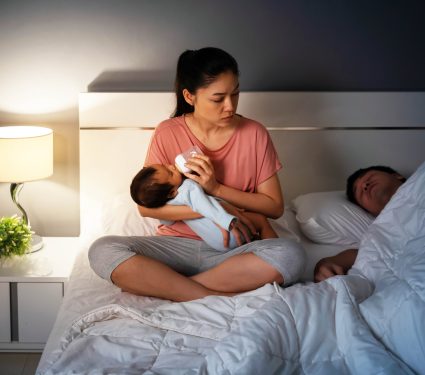 Tired,Mother,Feeding,Milk,Bottle,To,Newborn,Baby,While,Looking